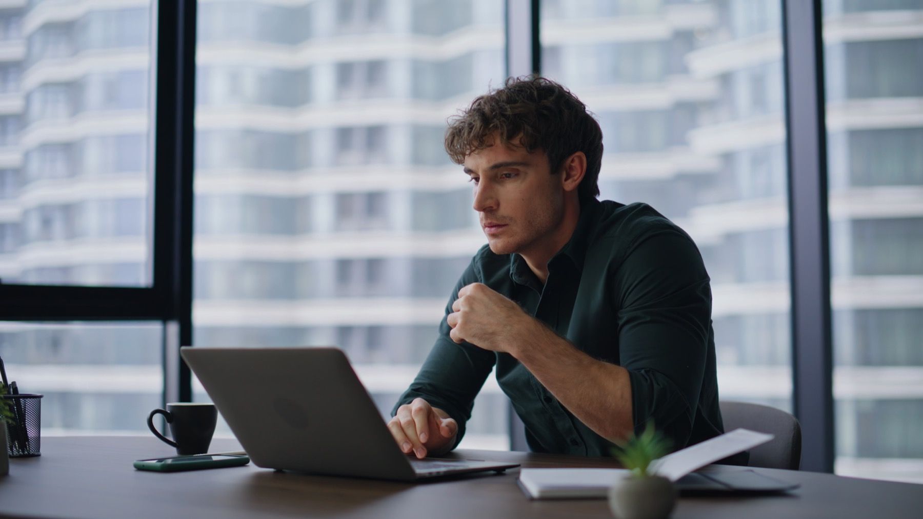 Person working at a laptop reviewing board documents.