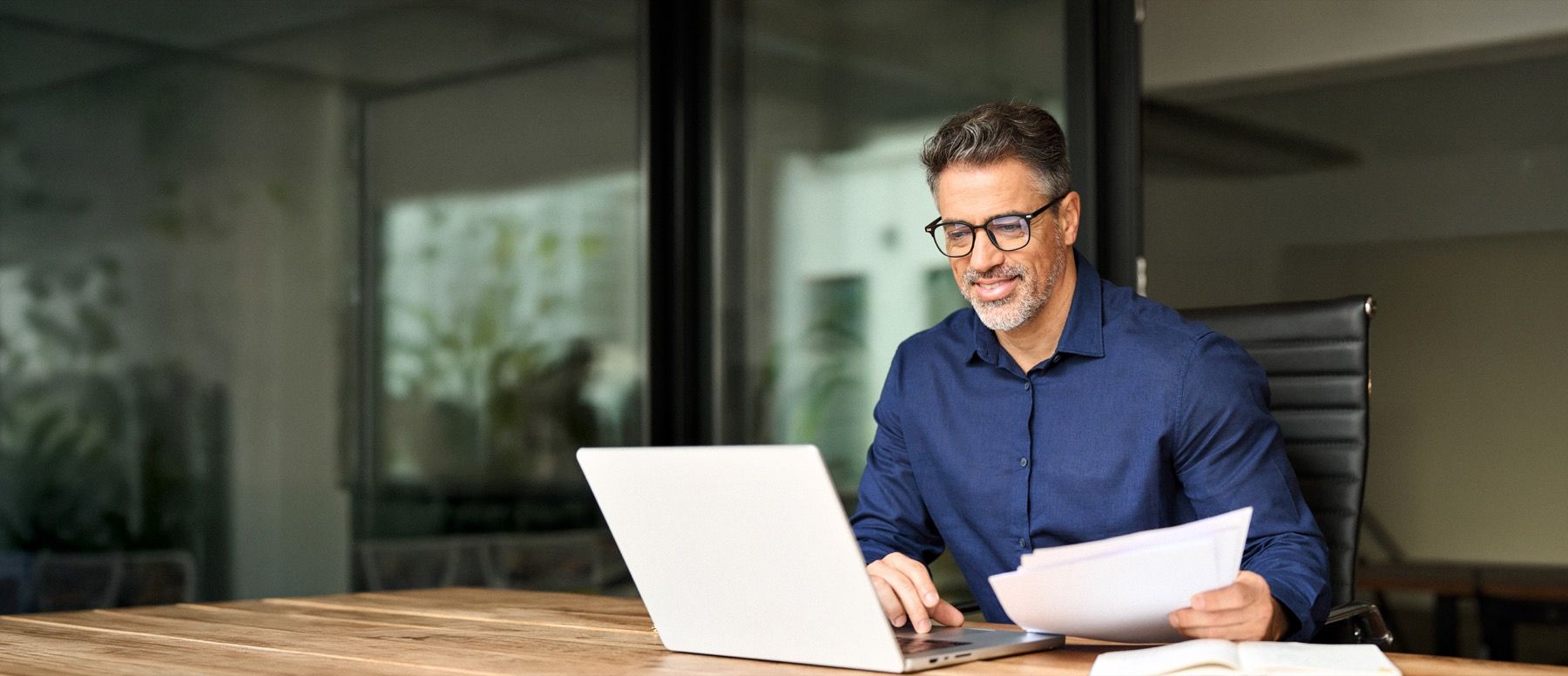 A director reviewing prepared board papers at a laptop.