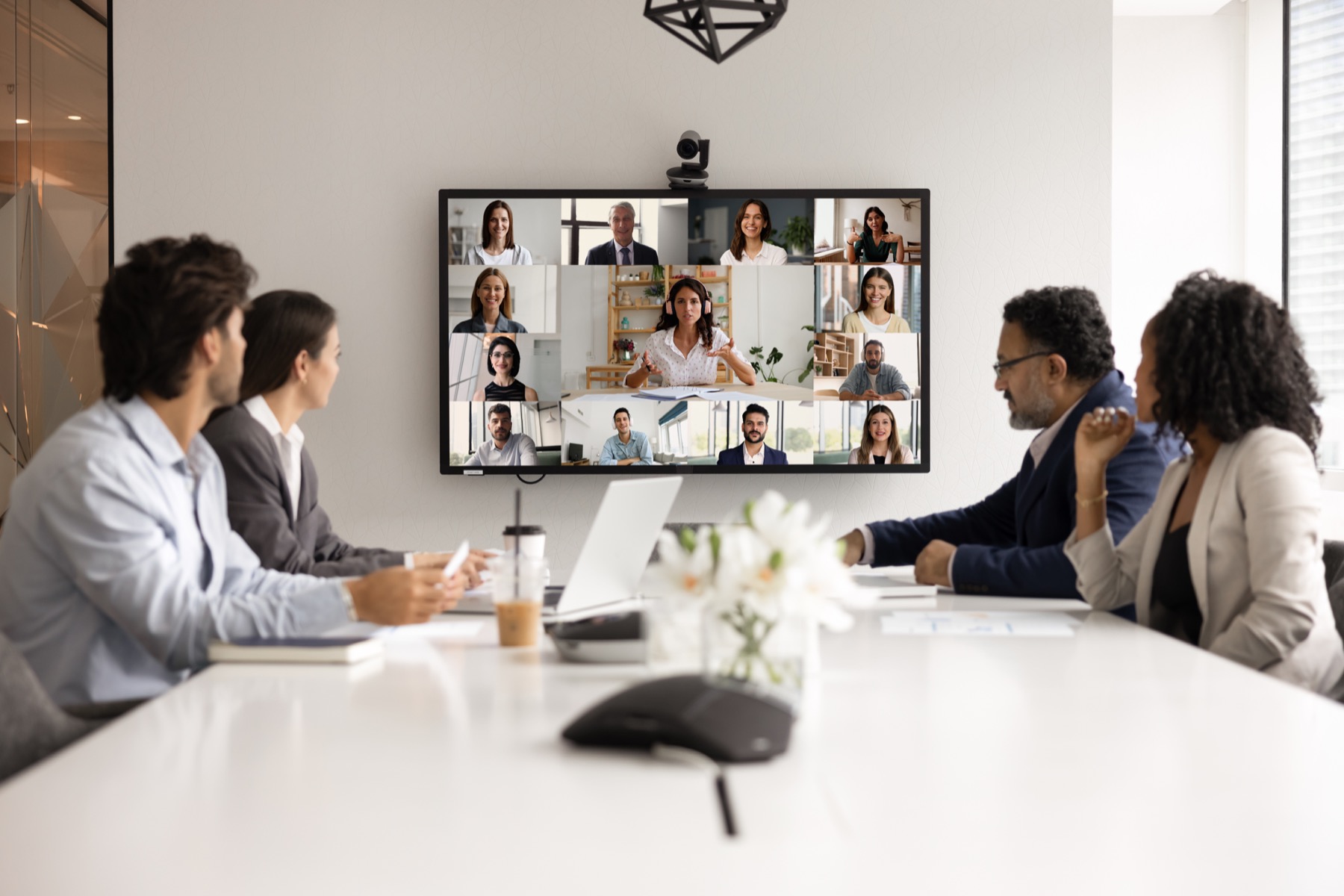 Hybrid board meeting with directors in the room and attendees on screen.