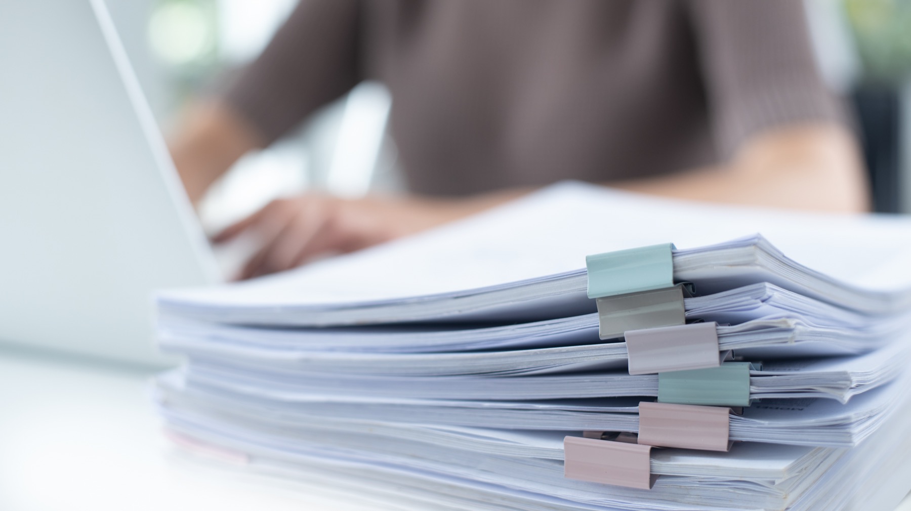 Stacked board papers beside a laptop.