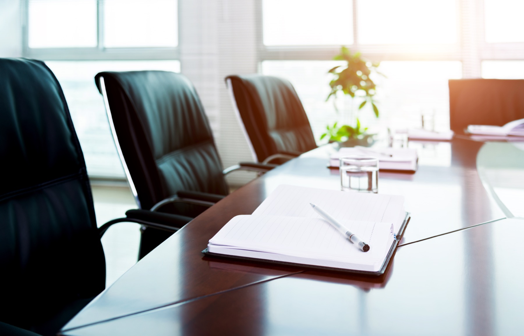 Boardroom table with papers and a pen prepared before a meeting.